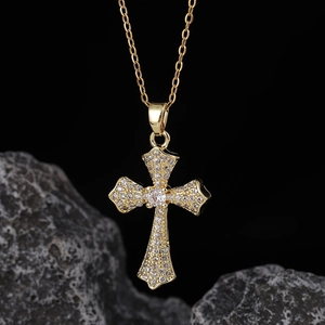 Collana con croce vintage placcata oro e pavé di zirconi su uno sfondo di roccia scura