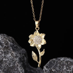 Macro shot of gold flower pendant with white zircons on dark stone background