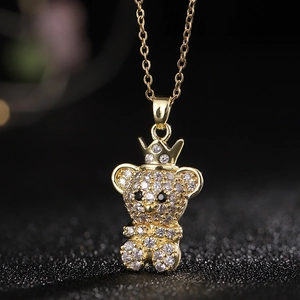 Vista macro del colgante de oso de peluche bañado en oro con corona y piedras de circonita