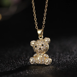 Foto macro de colgante de oso bañado en oro con pavé de circonitas y lazo detalle