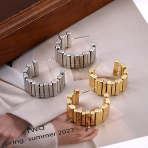 Unregelmäßige geometrische C-Ohrstecker aus Metall in Gold und Silber auf einem Magazin