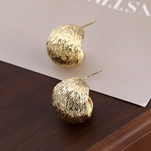 Nahaufnahme goldener C-förmiger gehämmerter Ohrringe mit S925 Silberstempel-Prägung