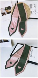 Detail of pink and dark green knit scarf with contrast heart patterns and soft texture