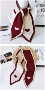 Detail of red and white knitted scarf featuring heart patterns and pointed triangle ends