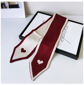 Close-up of knit scarf with heart patterns and pointed ends in wine red and cream