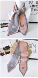 Close-up of pink and grey knit scarf with heart jacquard pattern and pointed ends