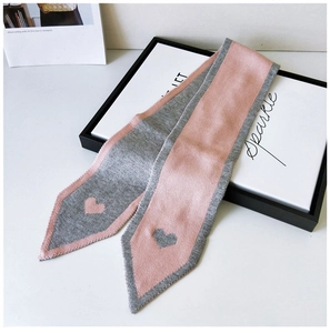 Detail of pink and grey knitted twilly scarf with heart pattern on a gift box