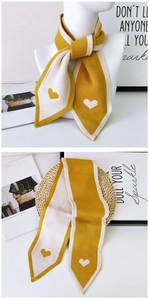 Detail of knit scarf showing yellow and beige contrast with heart patterns and pointed ends