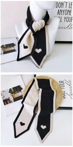 Detail of knit scarf showing the contrast heart pattern and pointed ends in black and white