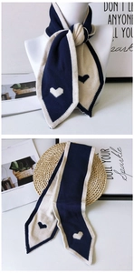 Detail of navy and cream knit scarf with heart embroidery and sharp angled ends