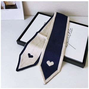 Close-up of navy and cream knit skinny scarf featuring heart jacquard and contrast stitching