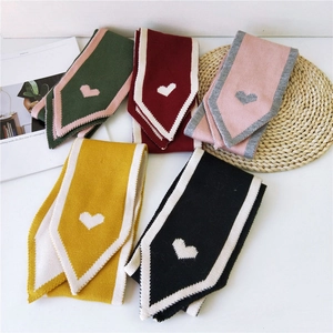 Knitted winter scarves with heart pattern in five vibrant colors laid on a table