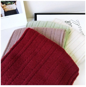 Close-up of thick ribbed knit scarves in red, purple, green, and cream soft textures
