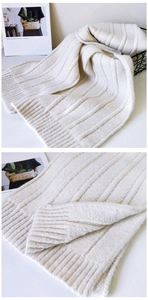 Detail of cream white ribbed knit scarf showcasing thick warm texture and soft fabric material
