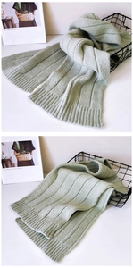 Close-up of sage green ribbed knit scarf with soft wool texture in a minimalist setting