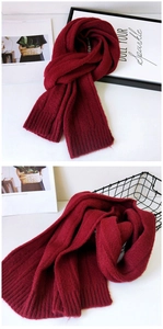 Detailed close-up of dark red knitted scarf texture and ribbed edge finish