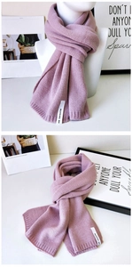 Detail eines mauvefarbenen Strickschals mit Rippbündchen und Marken-Webetikett