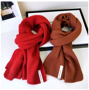Detail von roten und karamellfarbenen Strickschals mit gewebten Etiketten und weicher Wolle