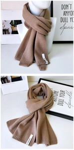 Detail eines braunen Strickschals mit gewebtem Kollektionslabel und Rippkanten