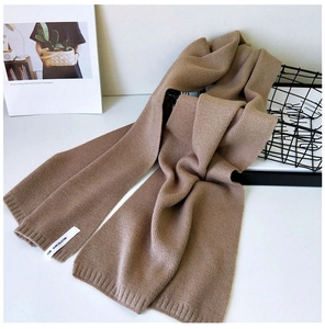 Details der braunen Strickschal-Textur mit Rippbündchen und minimalistischem Logo-Etikett