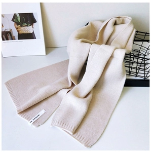 Detailansicht eines cremefarbenen Strickschals mit Rippkante und modischem Etikett