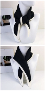 Close-up of black knitted scarf with white trim detail on a mannequin neck