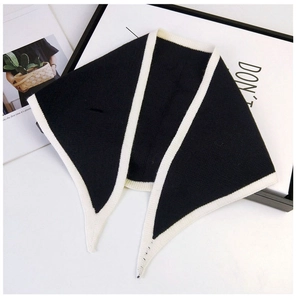 Detail of black knitted triangle scarf with white contrast trim on a minimalist background