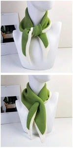 Detail of green knitted triangle scarf with contrast white trim and soft texture