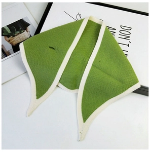 Close-up of grass green knitted scarf with white trim and functional cross-through slit