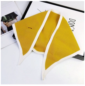 Detailed knit texture of the yellow triangular scarf with white contrast edges