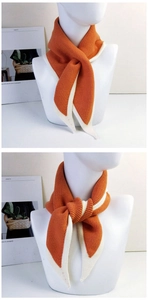Detail view of the orange knitted scarf showing two different styling methods on a mannequin