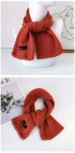 Détail de l'écharpe en maille rouge rouille avec bouton et étiquette de marque