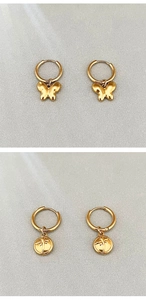 Détail de boucles d'oreilles papillon dorées et pendentifs ronds gravés d'insectes