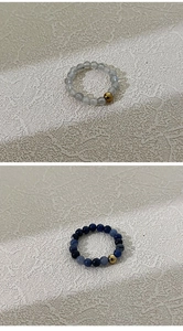 Detail van 4mm natuursteen kralen elastische ringen in grijs en blauw met goud
