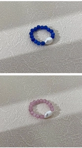 Detail of handcrafted beaded rings with cat eye beads and baroque pearls in blue and pink
