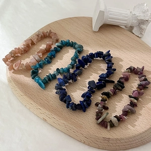 Collezione di braccialetti in scaglie di pietra naturale su un vassoio in legno minimal