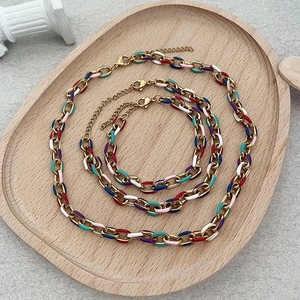 Parure de bijoux avec chaîne en émail coloré et or sur plateau minimaliste