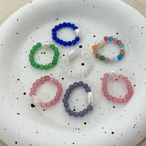 Chic cat-eye bead rings set with baroque pearls displayed on a ceramic dish