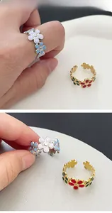 Detail of adjustable colorful enamel flower rings in silver and gold plating
