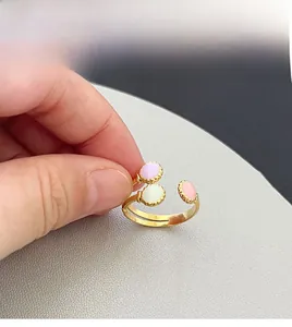 Détail d'une bague dorée ajustable avec trois pierres ovales colorées et bordures perlées