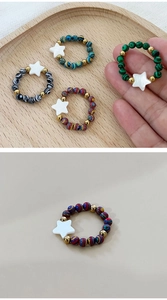 Gros plan de bagues en perles colorées avec breloques étoiles blanches et perles dorées