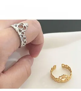 Detalle de los anillos abiertos en forma de corona plateado y dorado con motivos de corazón