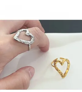 Detailed view of gold and silver hammered open rings with hollow heart design on a hand