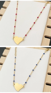 Detailed close-up of gold beaded chain necklace with vibrant red and blue heart pendants