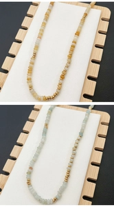 Detail of handmade beaded necklace with natural colorful gemstones and gold disc spacers
