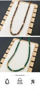 Detail of tiger eye and malachite beaded necklaces with golden spacers on wood stand