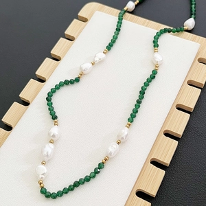 Collana con perle barocche e perline verdi sfaccettate su supporto per gioielli in legno