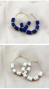 Detail of Bohemian gold hoop earrings with blue and white Heishi clay beads on silk