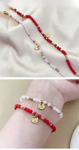 Detail of red and pink beaded 18K gold plated stainless steel bracelets with hammered charms