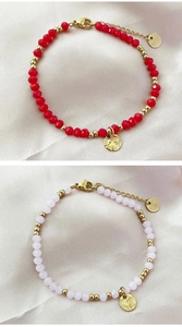 Detail of handmade beaded bracelets with red pink stones and 18K gold discs